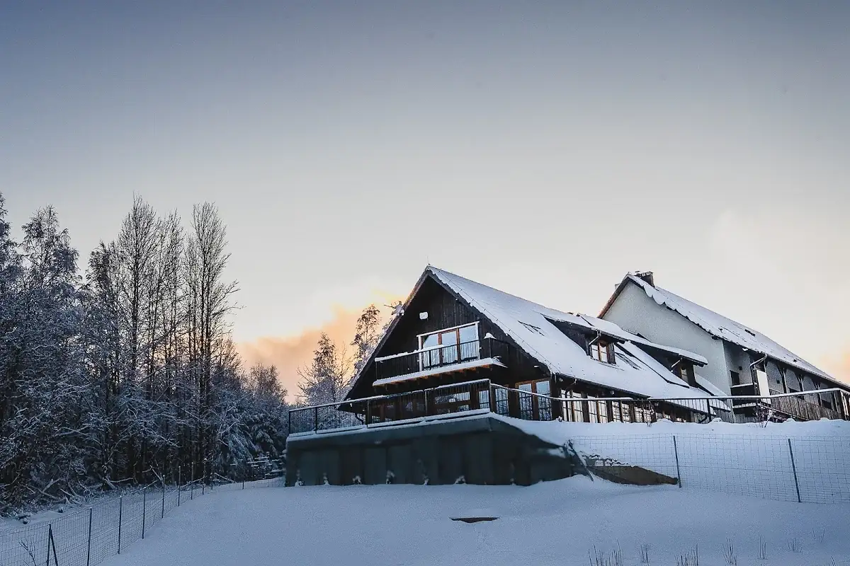 Budynek pensjonatu Owca z widokiem oświetlony zimową nocą.