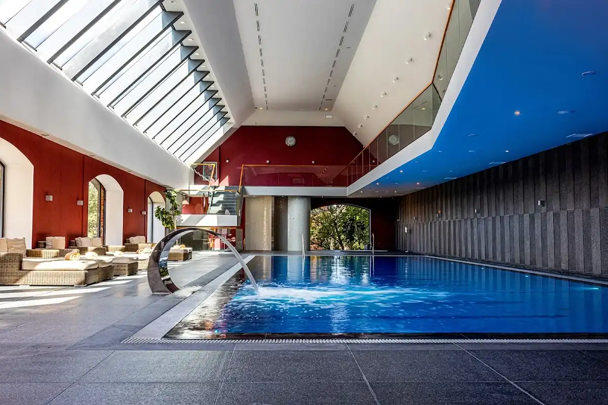 Błękitny basen pod łukowym sklepieniem, oświetlenie i kolumny.