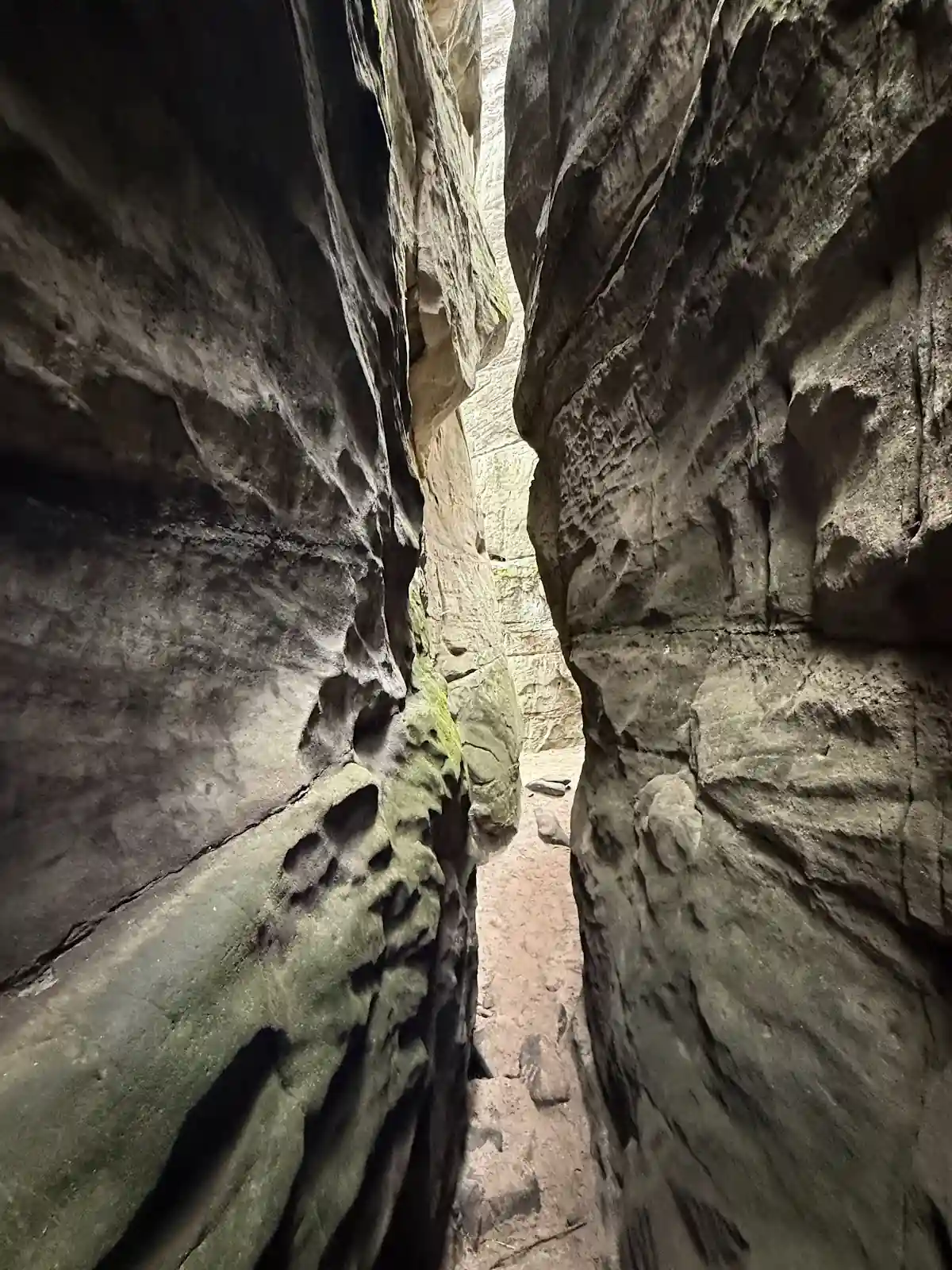 Wąskie przejście w szczelinie skalnej na Ostašu, pionowe ściany piaskowca.