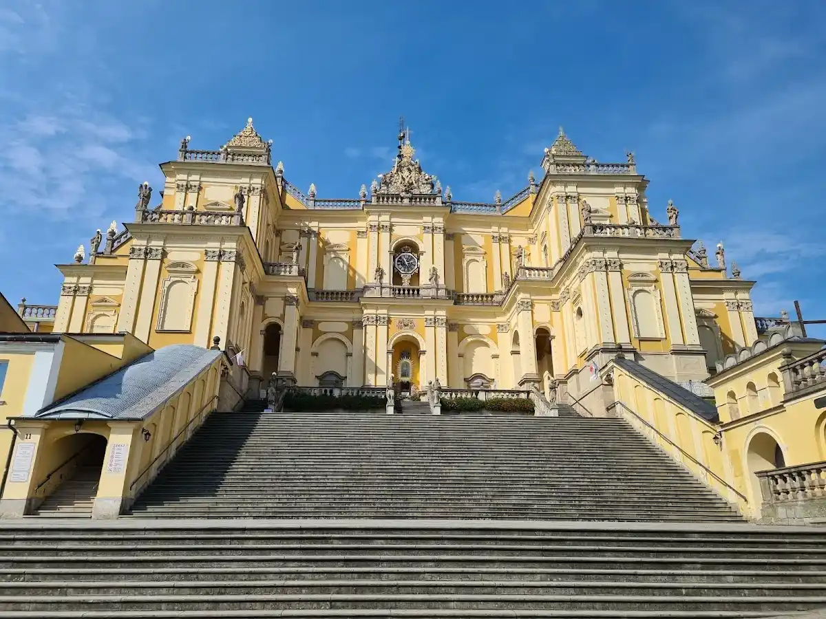 Monumentalna fasada bazyliki w Wambierzycach oświetlona wieczorem.