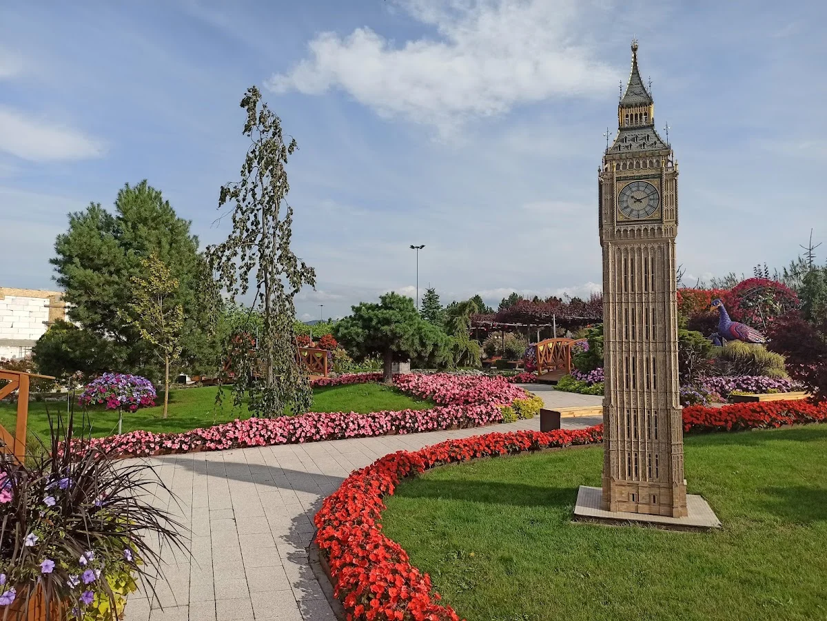 Wąska wieża miniaturowa na tle trawnika.