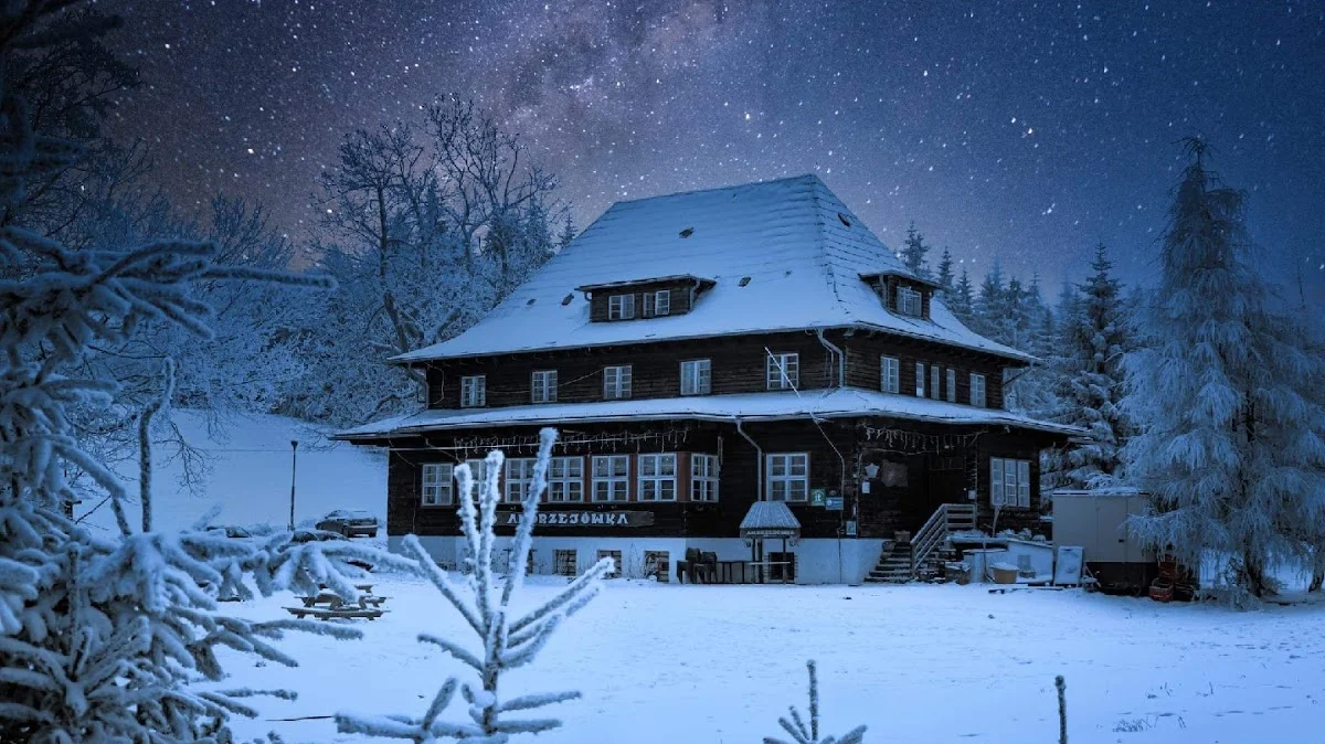 Oświetlony budynek pensjonatu w zimowej aurze nocą.