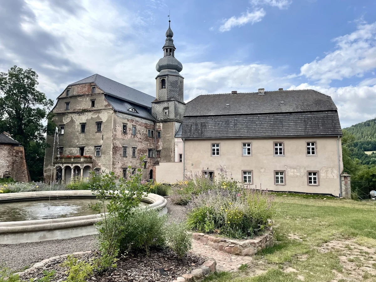 Okazały pałac z wieżyczkami otoczony parkiem.