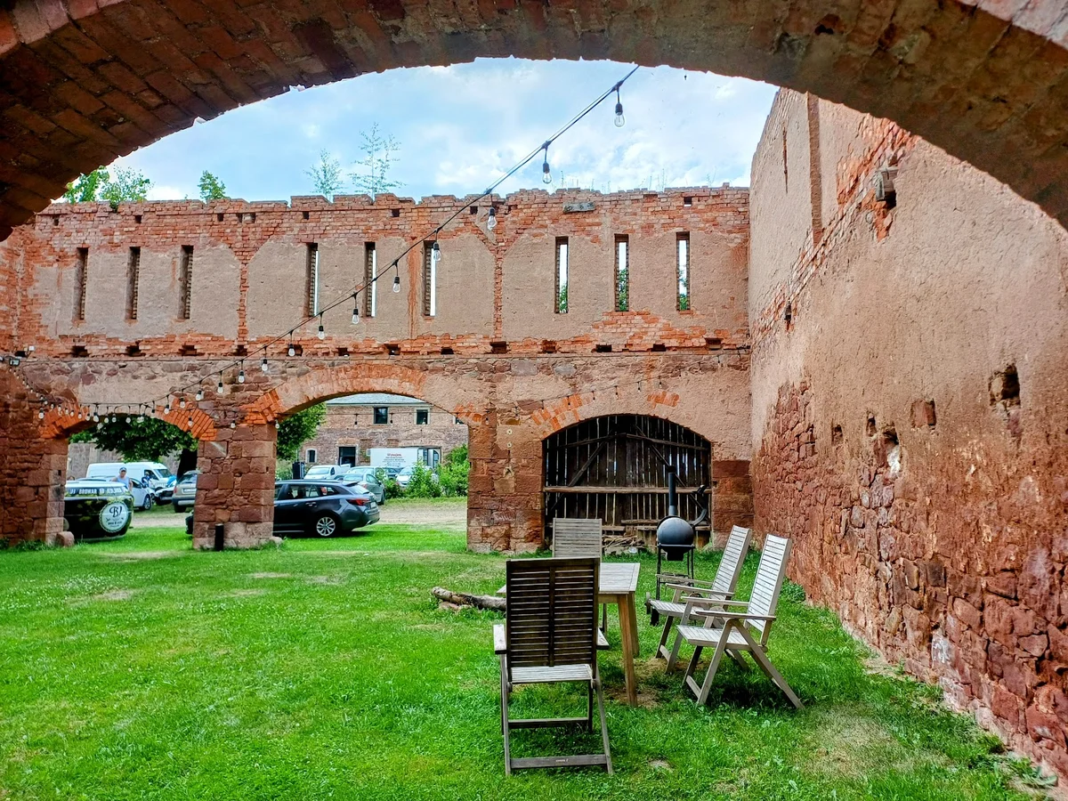 Dziedziniec zamkowy z ławkami i roślinnością.