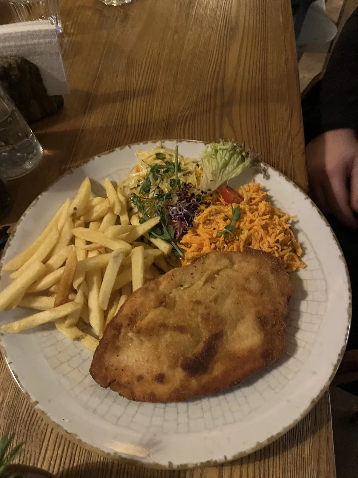 Duży kotlet z frytkami i surówką.