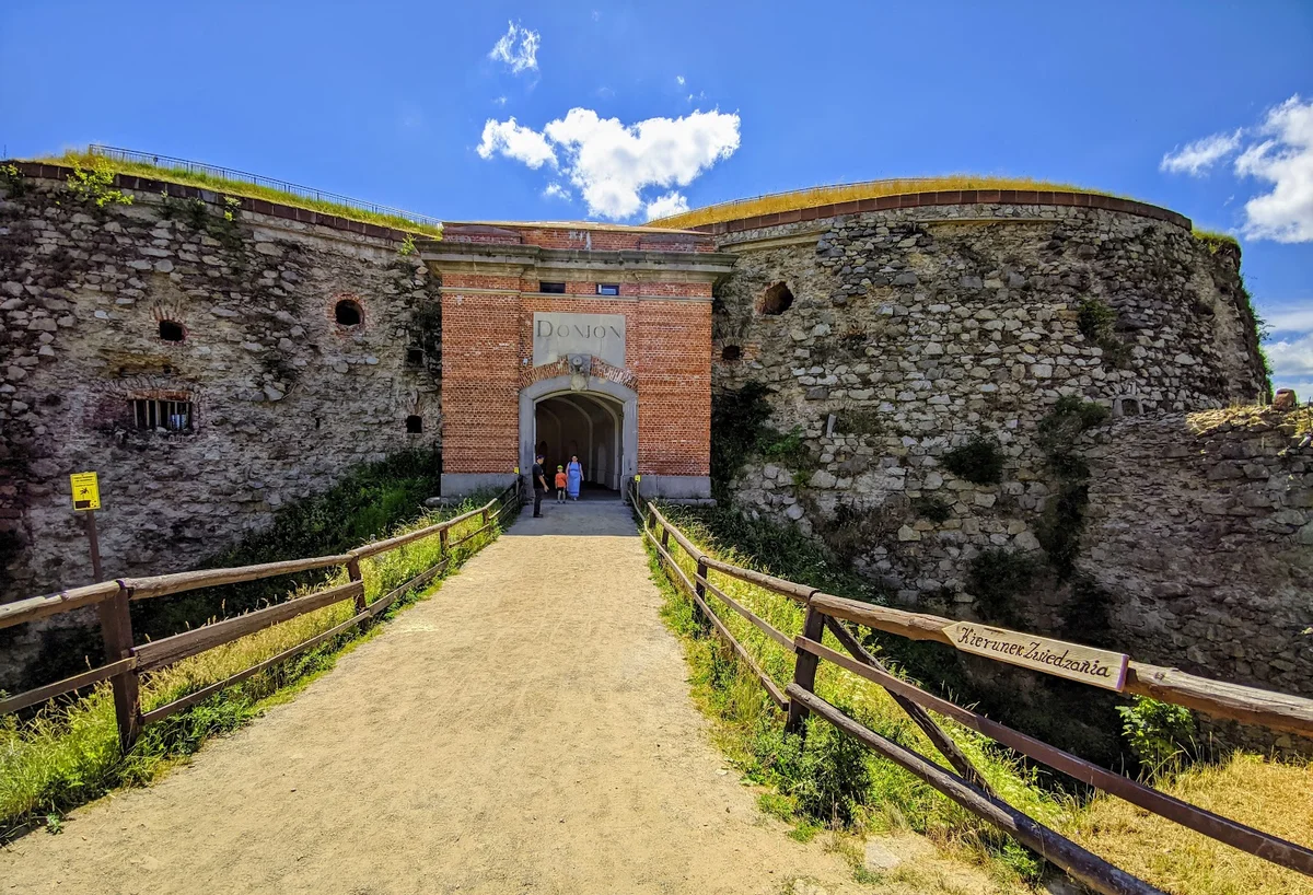 Fragment wejścia do zamku o zabytkowym charakterze pod słońcem pod niebem.