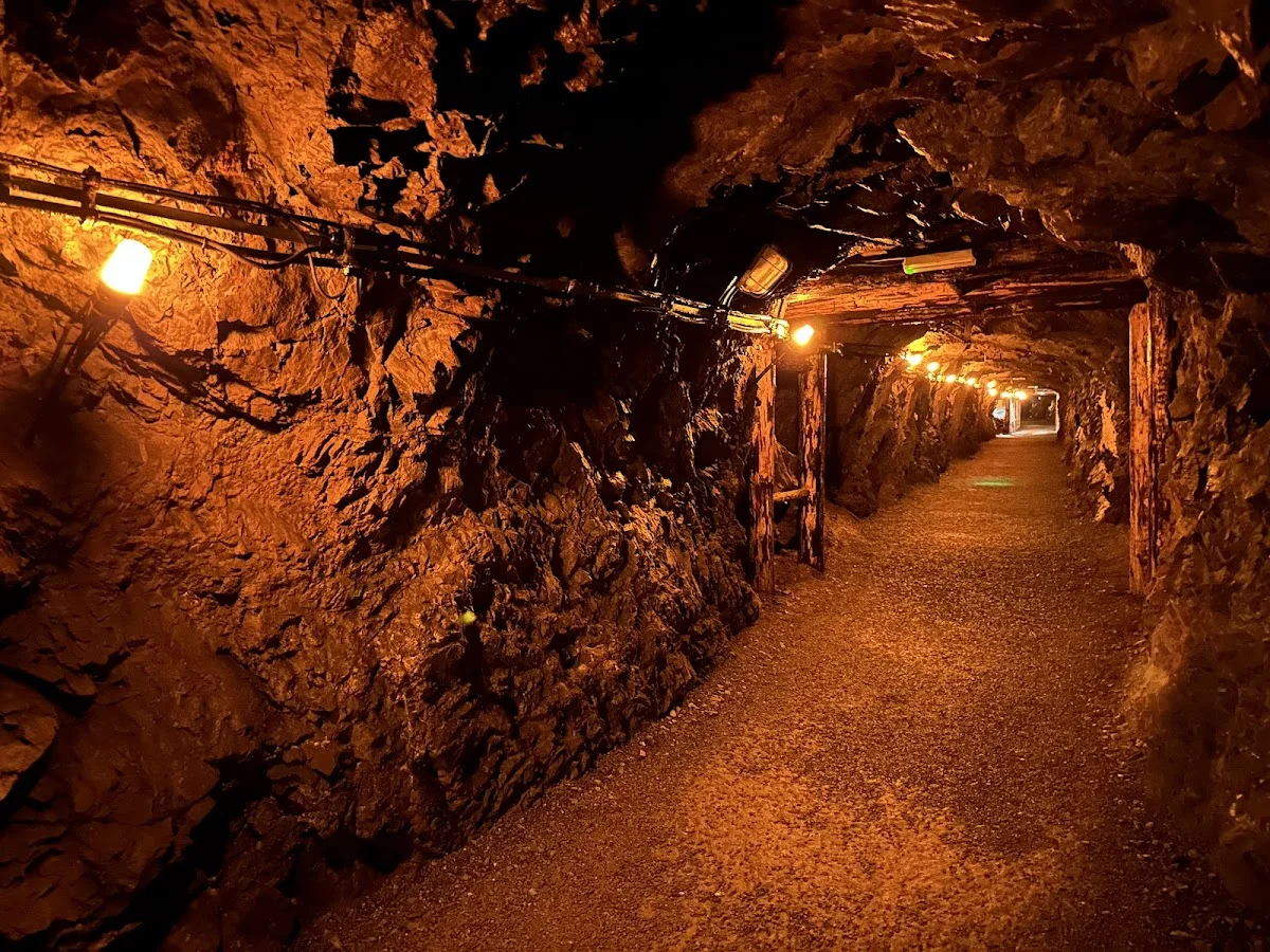 Oświetlone wnętrze zabytkowej kopalni z rzędami lamp o zmroku pod słońcem.