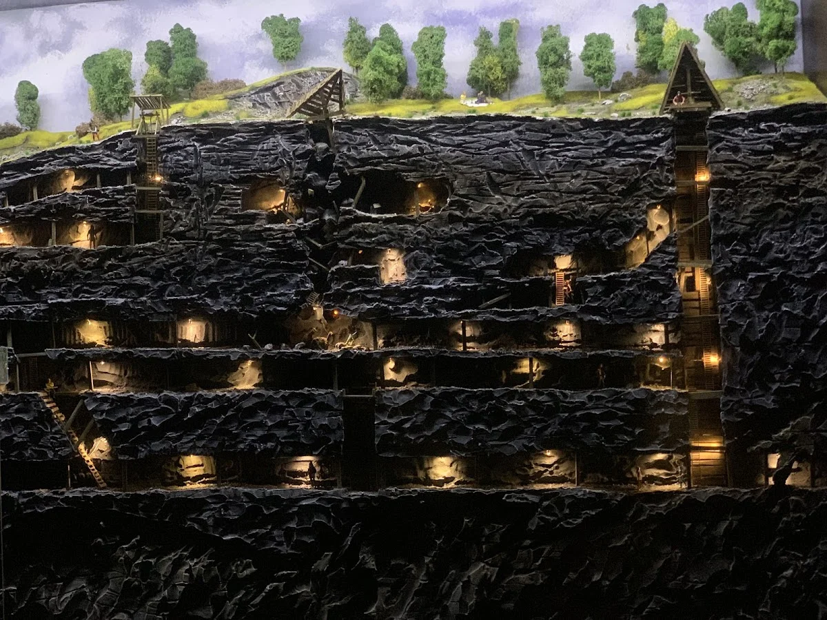 Fragment ściany w zabytkowej kopalni z rzędami drobnych światełek.