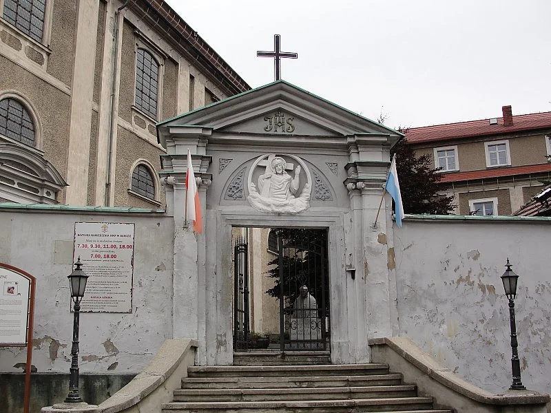 Mały biały kościółek o prostej formie pod niebem pod słońcem o świcie.