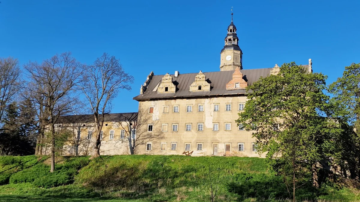 Panorama zamku na wzgórzu o słońcu pod niebem o świcie.