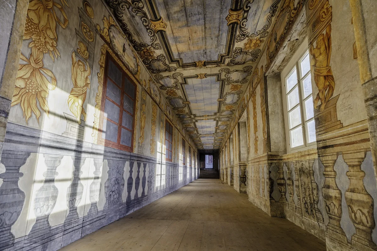 Długi korytarz z freskami w pałacu o wysokim standardzie pod słońcem.