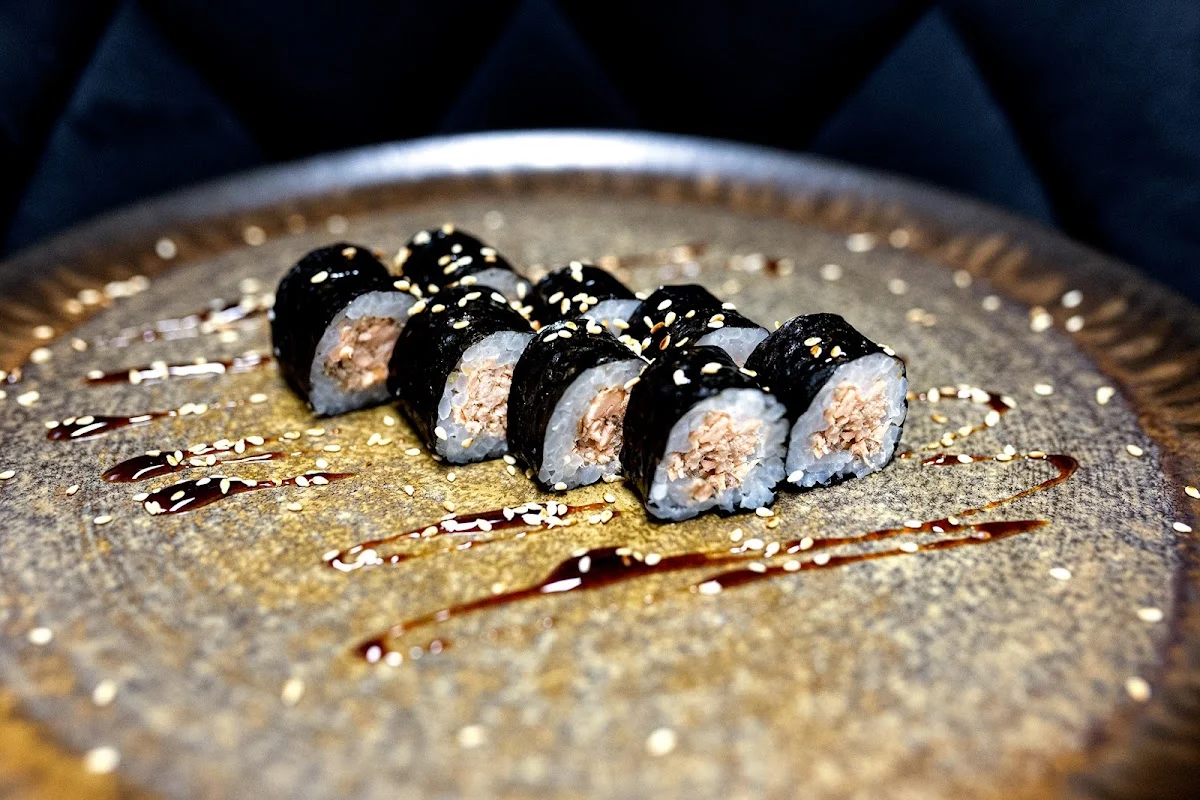 Sushi na ciemnym talerzu z dekoracją o wysokim standardzie.