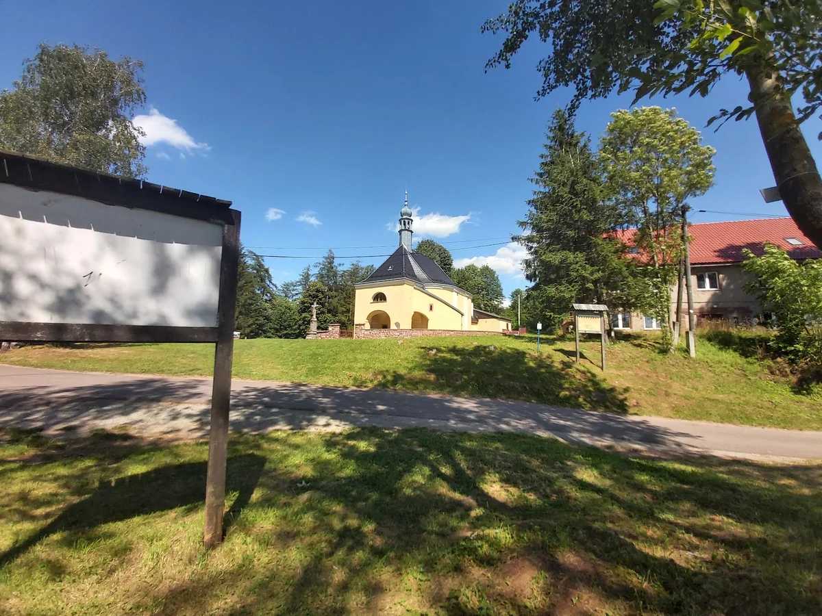 Tablica informacyjna przy starym kościele w słońcu.
