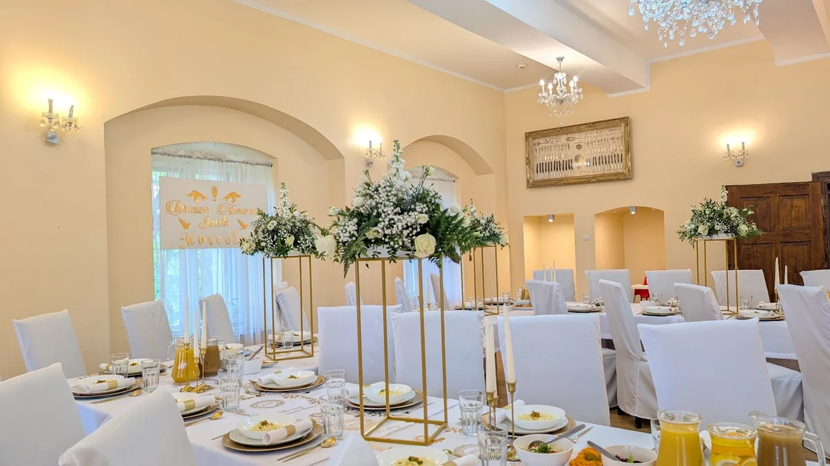 Uroczysta kolacja w białej sali w słońcu.